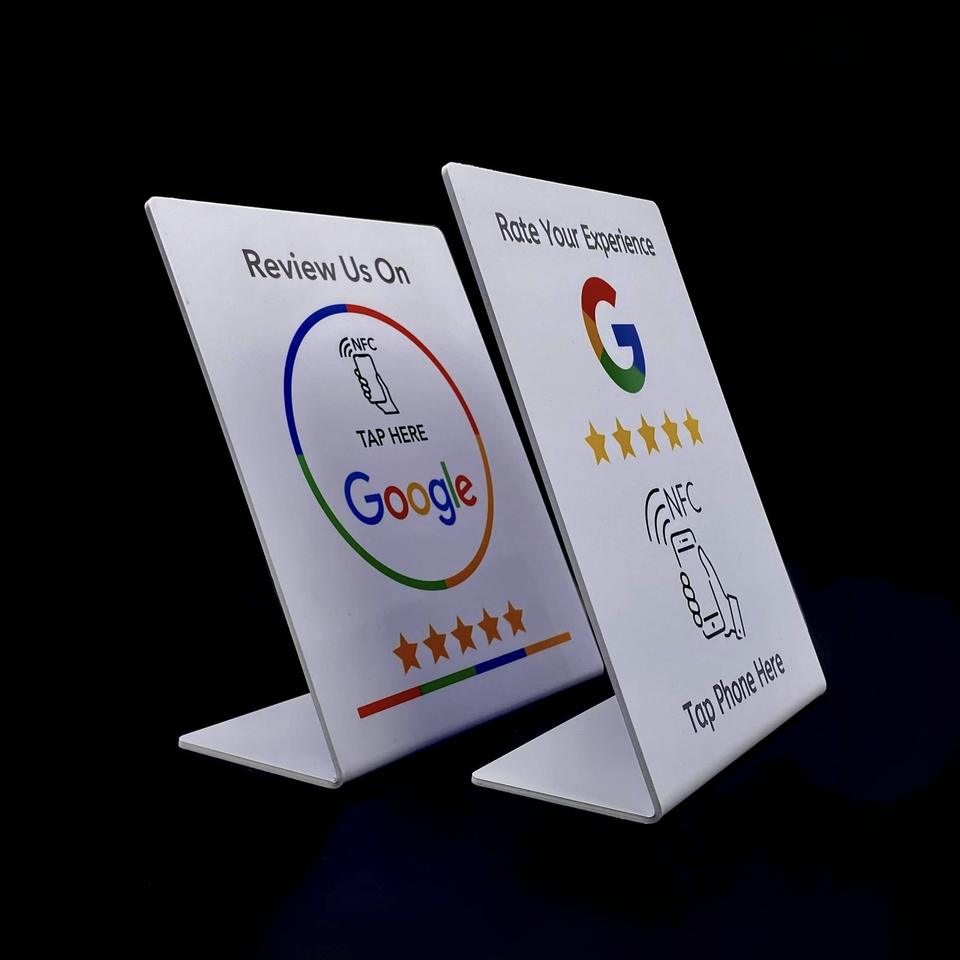 Dos tarjetas NFC de reseñas de Google con soporte en forma de L, fotografiadas sobre fondo negro